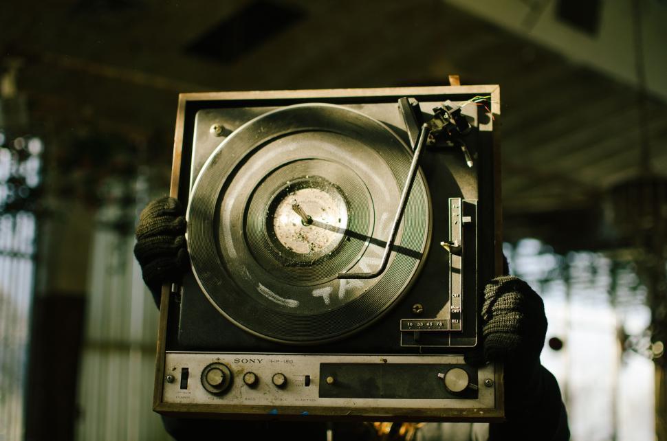 Free Image of Person Holding Up Record Player in Front of Window 