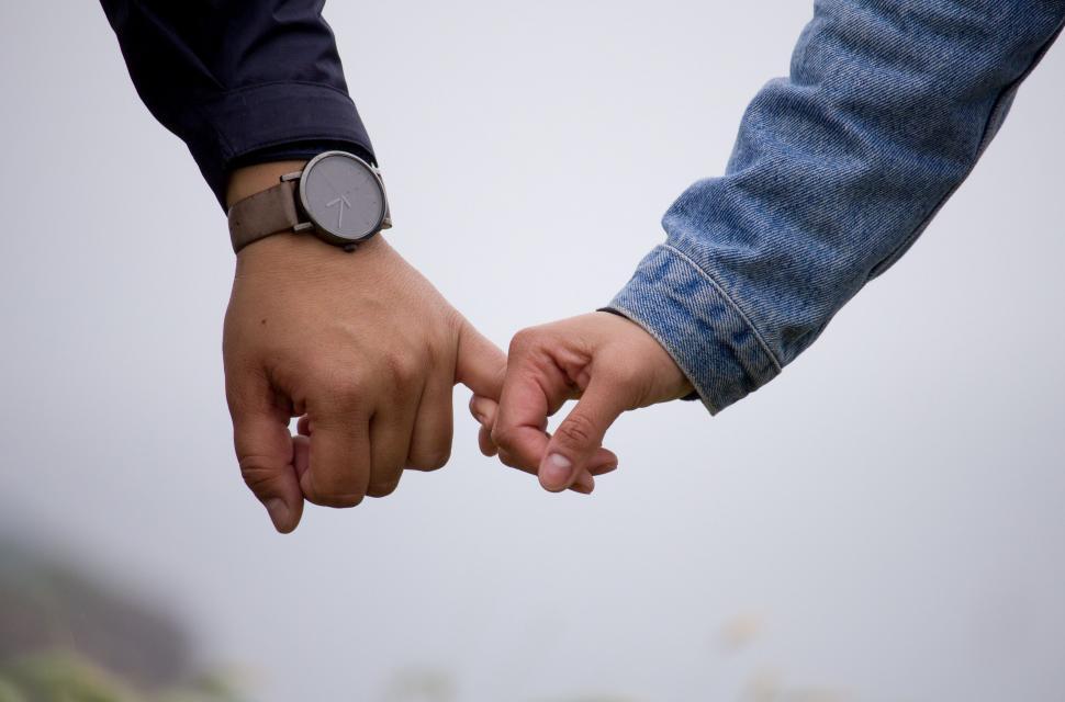 Free Image of Two People Holding Hands With City in Background 