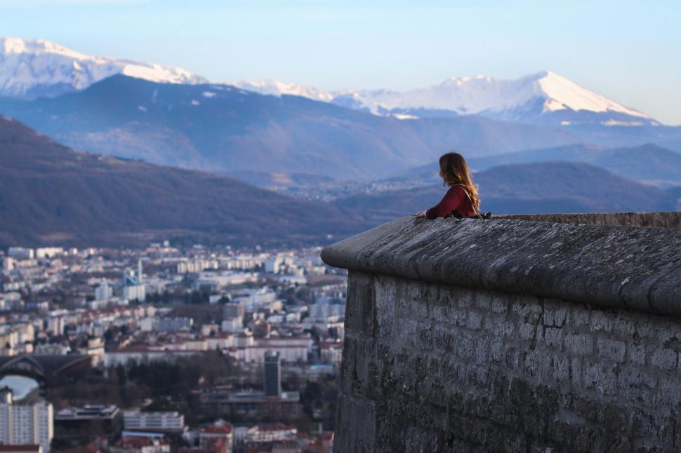 Free Image of Person Sitting on Ledge Overlooking City 