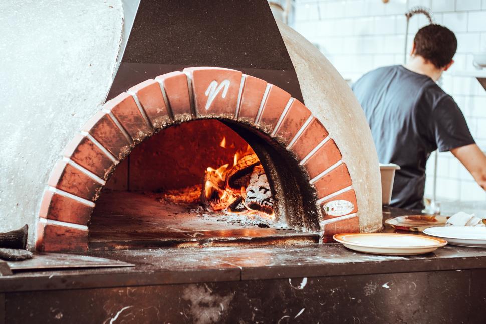 Free Image of Man Standing in Front of Brick Oven 