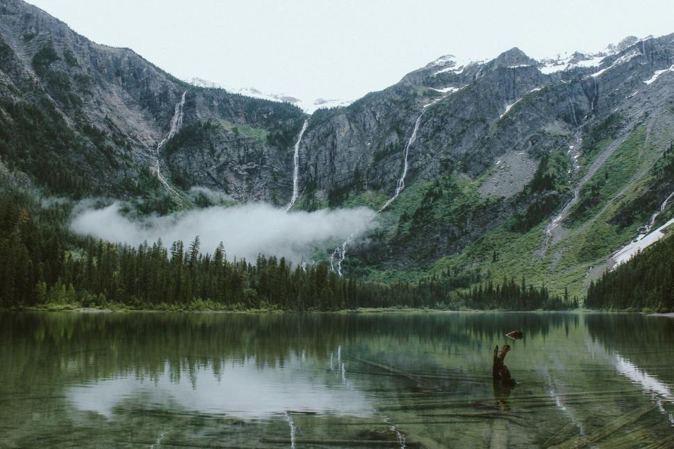 Free Image of Person Holding Umbrella By Lake Surrounded By Mountains 
