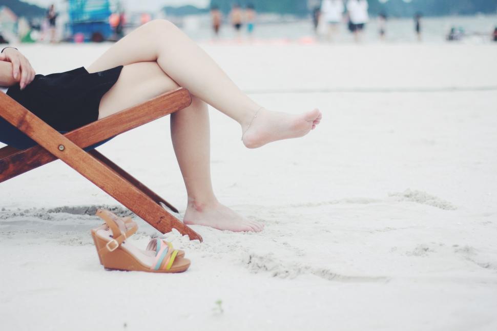 Free Image of Woman Sitting in Wooden Chair on Beach 
