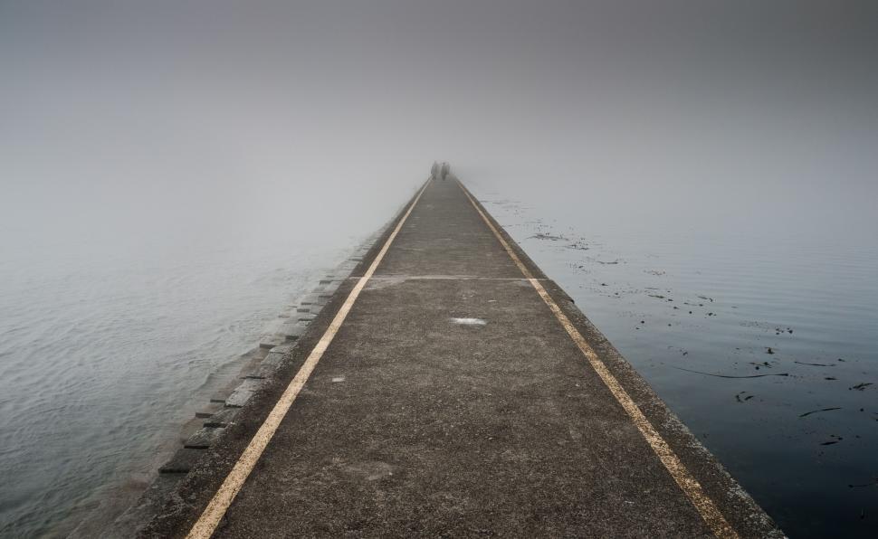 Free Image of Long Pier Extending Into Water on Foggy Day 