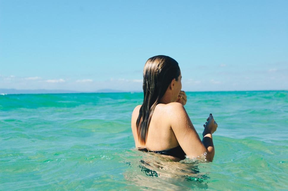 Free Image of Woman Sitting in Ocean Holding Cell Phone 