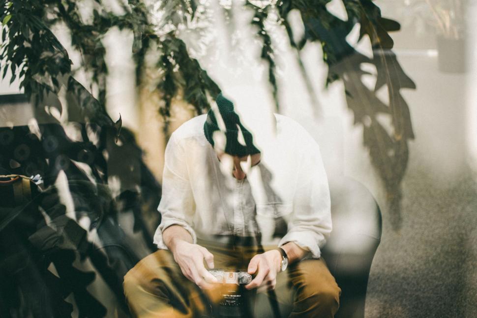 Free Image of Man Sitting on Bench in Front of Plant 