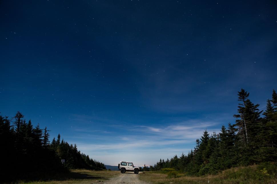 Free Image of Truck Driving Down Dirt Road Along Forest 