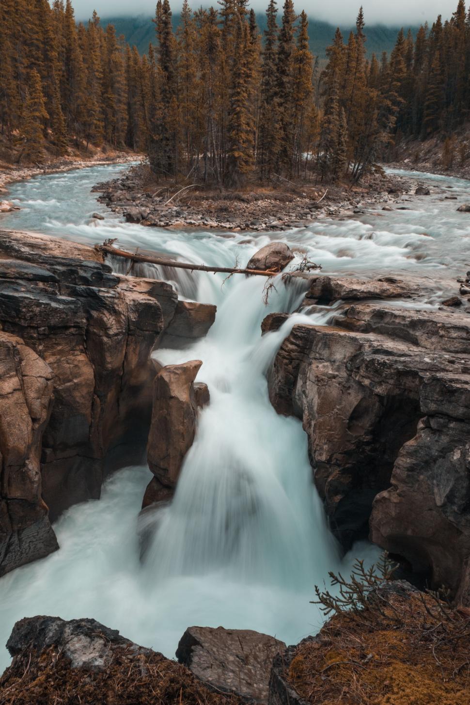 Free Image of Majestic Waterfall Flowing Through Forested River 