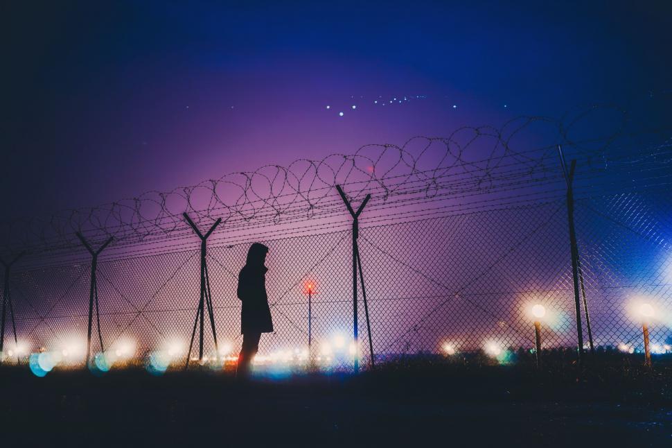 Free Image of Person Standing in Front of a Fence With Barbed Wire 