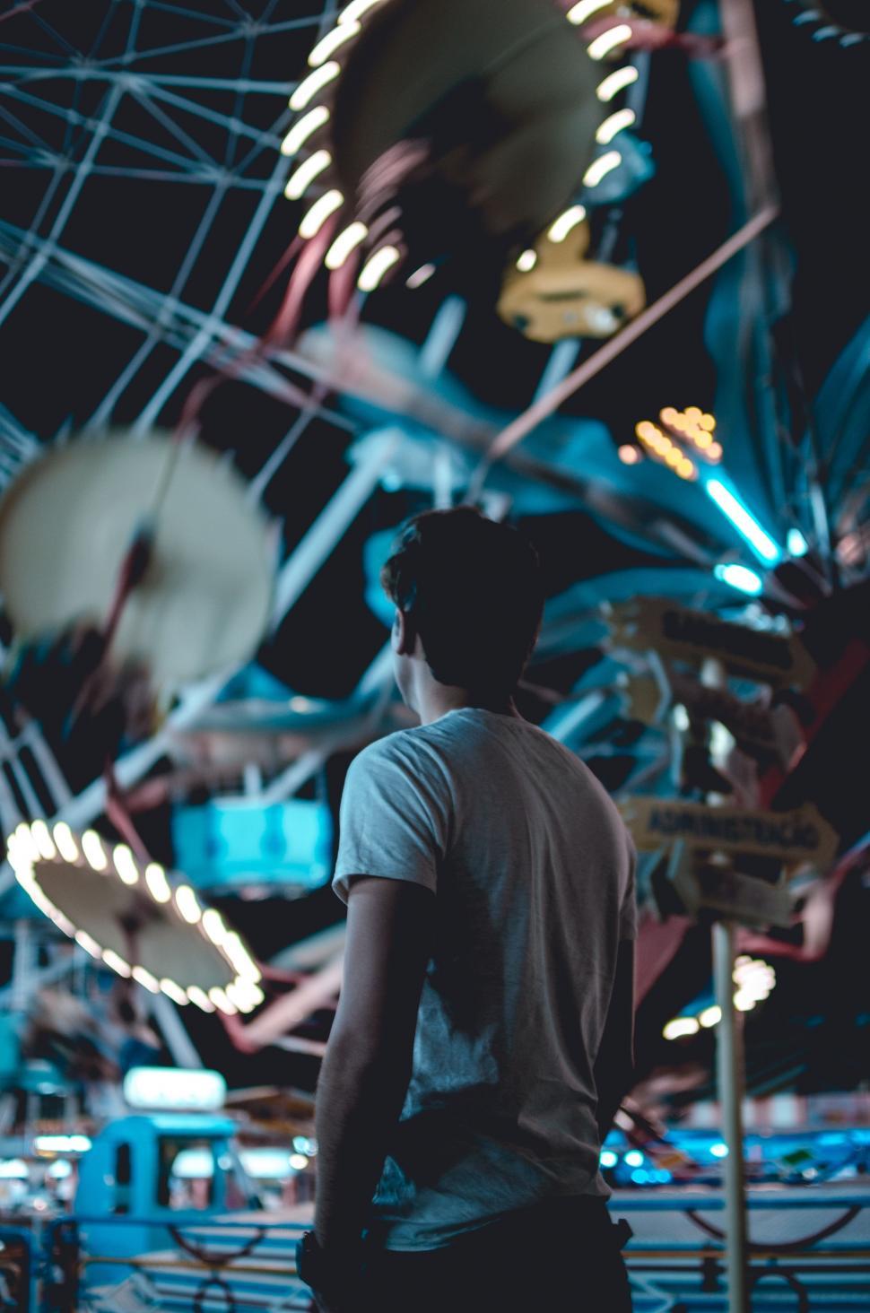 Free Image of Man Standing in Front of Carousel at Night 