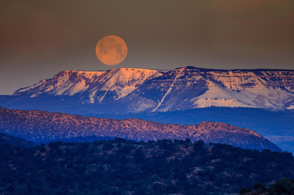 Free Image of Full Moon Rising Over a Mountain Range 