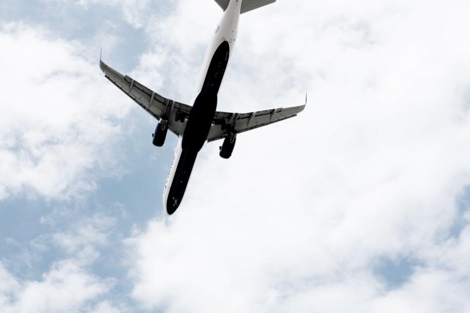 Free Image of Large Jetliner Flying Through Cloudy Blue Sky 