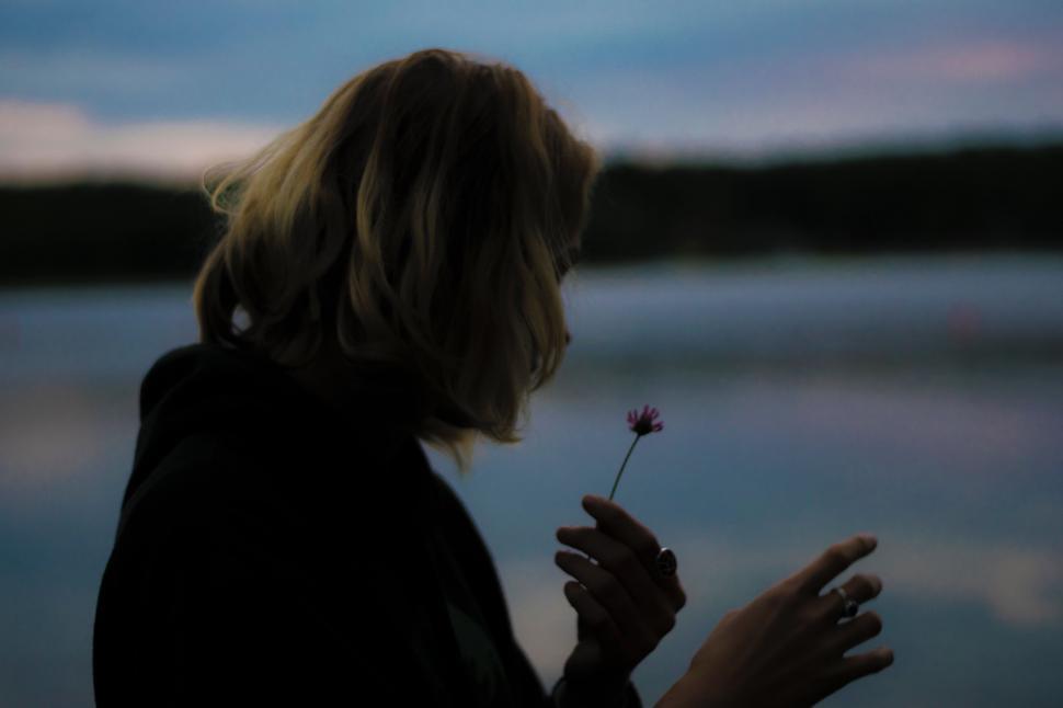 Free Image of Woman Holding Flower by Waterfront 