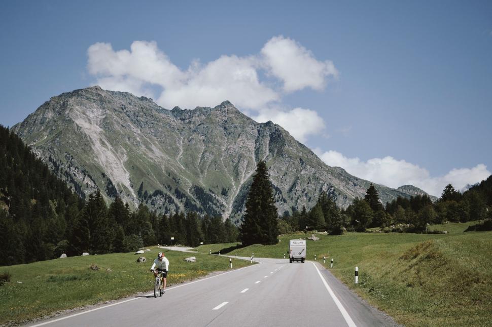 Free Image of Man Riding Bicycle Down Road Next to Mountain 