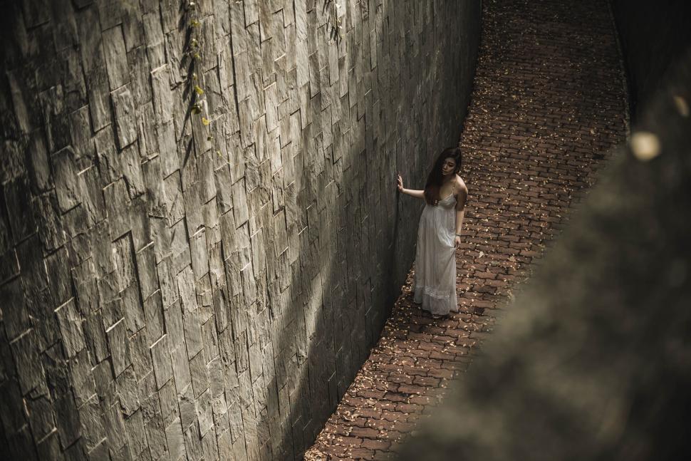 Free Image of Woman Standing Next to Stone Wall 