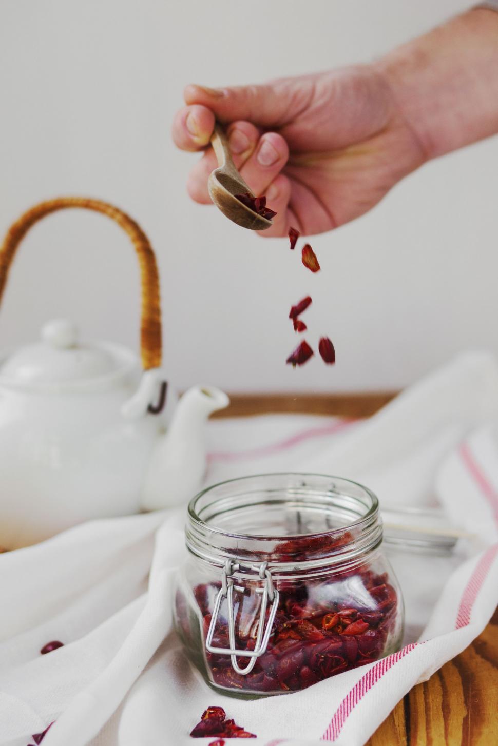 Free Image of Person Pouring Tea Into Glass Jar 