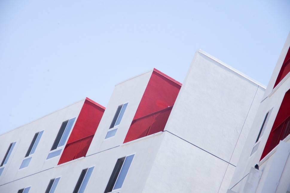 Free Image of Red and White Building With Windows Against Sky Background 