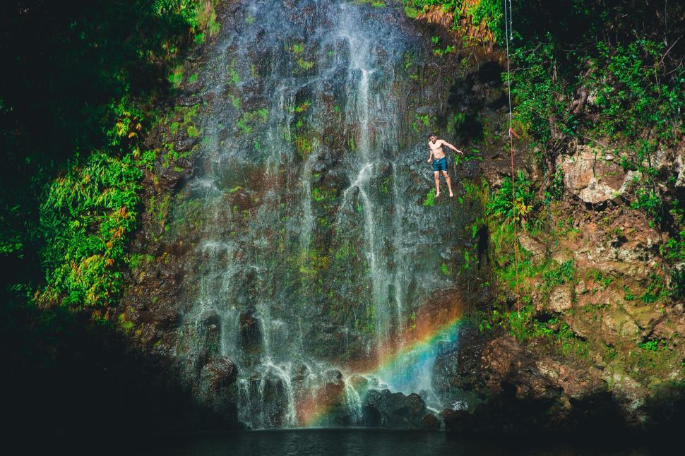 Free Image of Man Jumping Off Waterfall Into Lake 