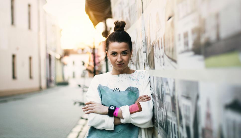 Free Image of Woman Leaning Against Wall With Arms Crossed 