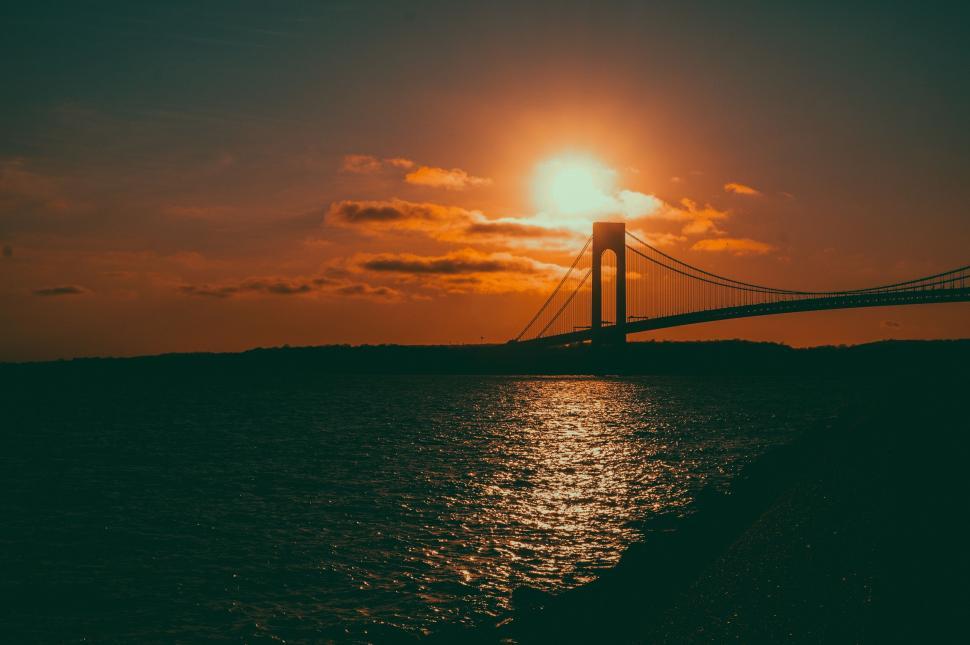 Free Image of The Sun Setting Behind a Bridge Over the Water 