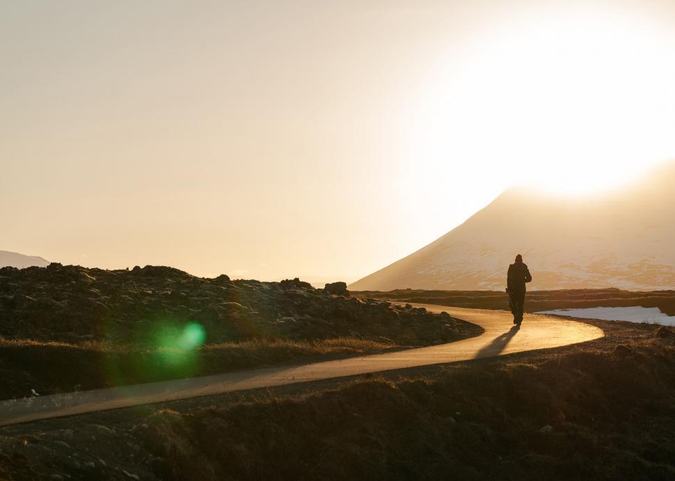 Free Image of Person Walking Down a Dirt Road at Sunset 