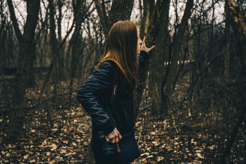 Free Image of Woman Standing in Woods Holding Onto Tree 
