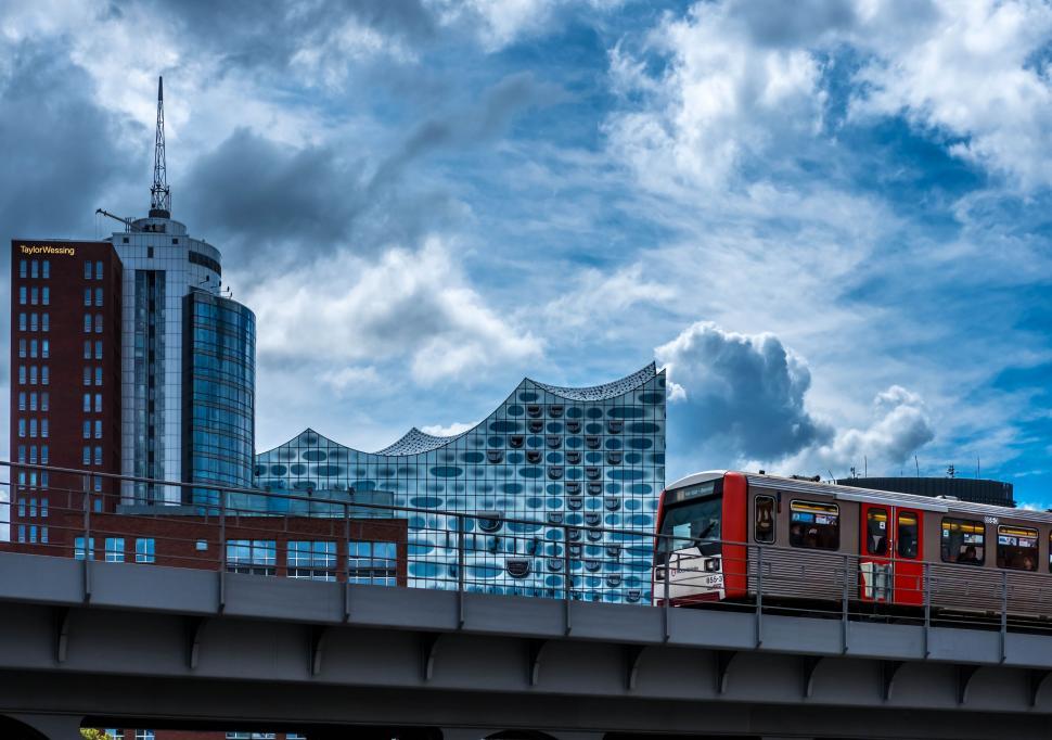 Free Image of Train Traveling Over Bridge With Tall Buildings in Background 