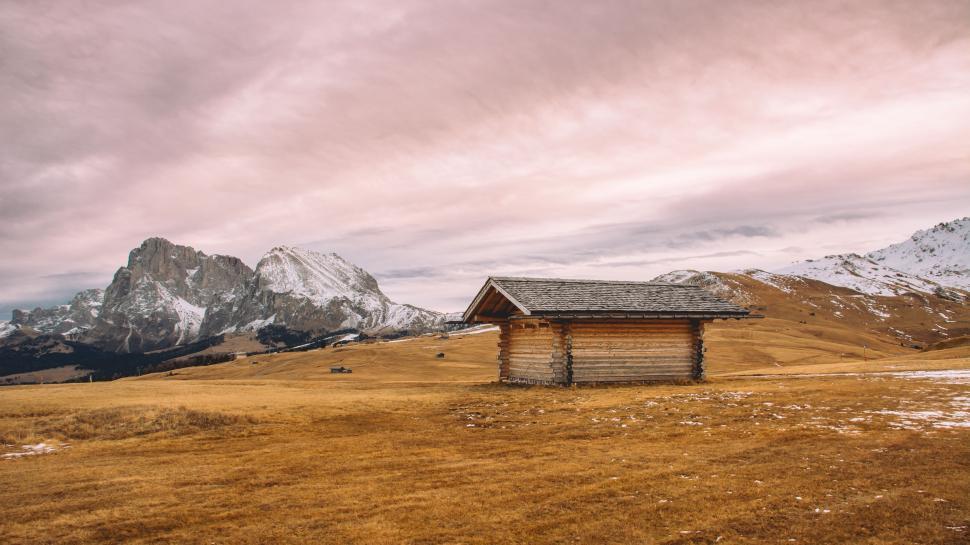 Free Image of Small Cabin in Field With Mountain Backdrop 