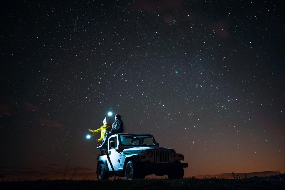 Free Image of Man Standing on Truck Under Night Sky 