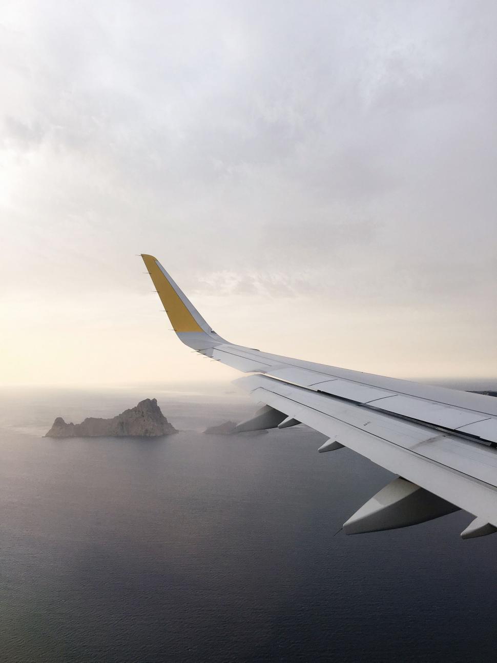 Free Image of Airplane Wing Flying Over Body of Water 