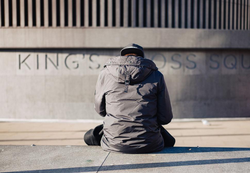Free Image of Person Sitting on Ground in Front of Building 
