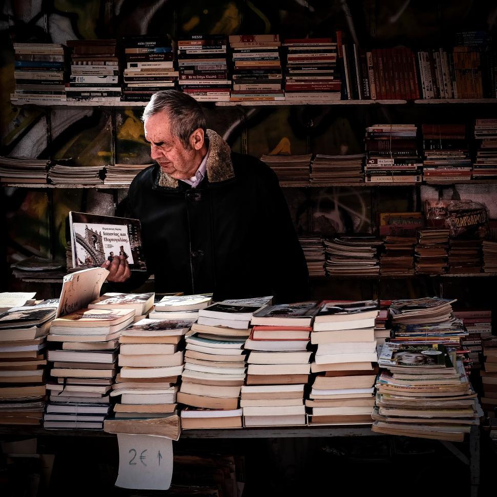 Free Image of Man Sitting at Table With Stacks of Books 