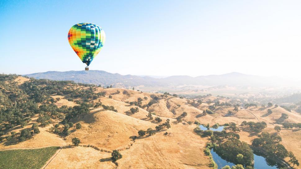 Free Image of Hot Air Balloon Flying Over Lush Green Hillside 