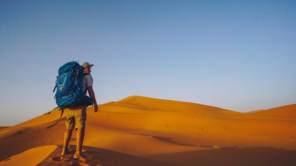 Free Image of Man Walking Across Desert With Backpack 
