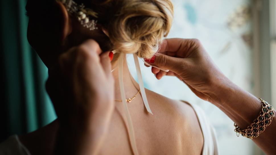 Free Image of Woman Putting on a Pair of Earrings 