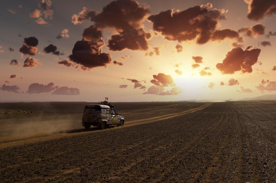 Free Image of Truck Driving Down Dirt Road Under Cloudy Sky 
