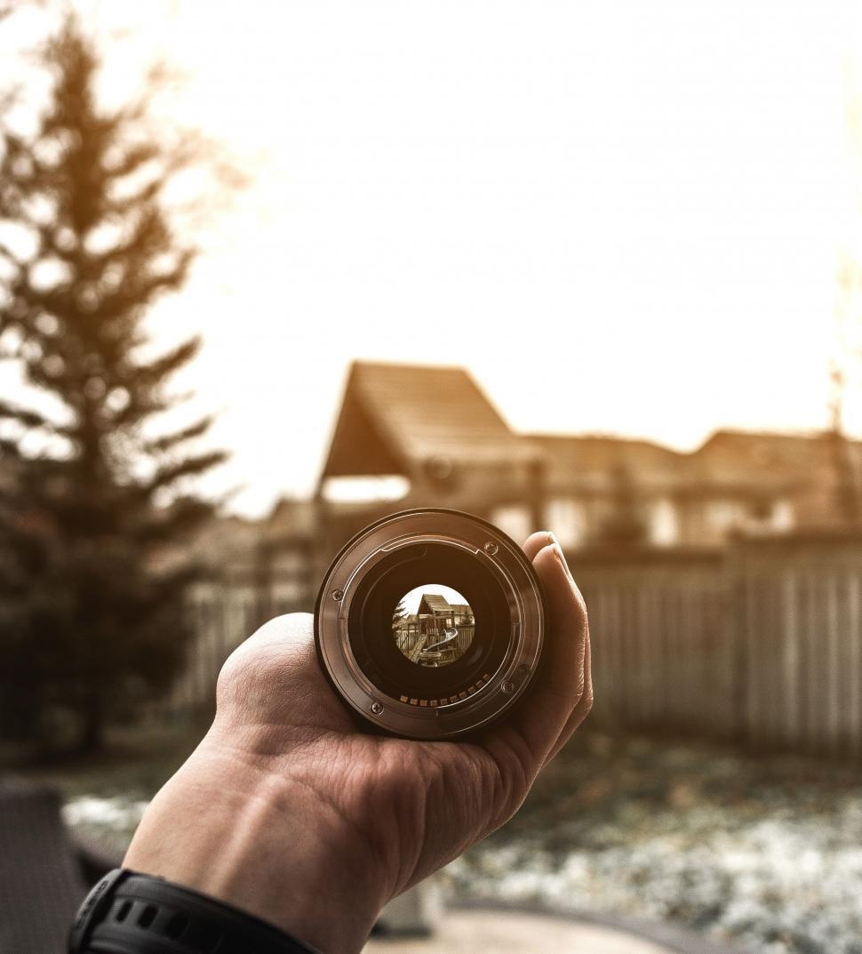 Free Image of Hand Holding Camera With House in Background 