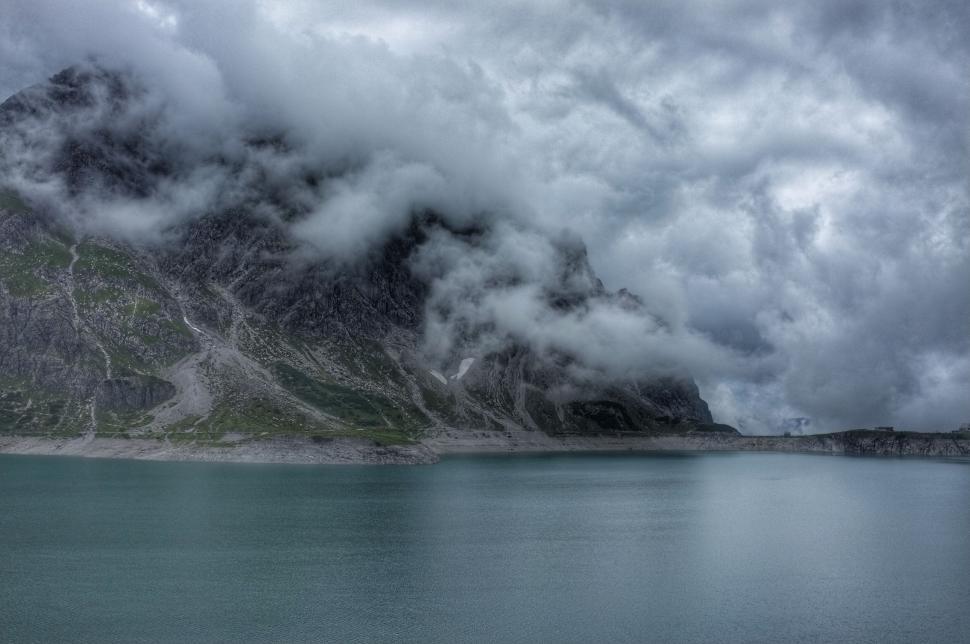 Free Image of Cloud-covered Mountain Beside Body of Water 