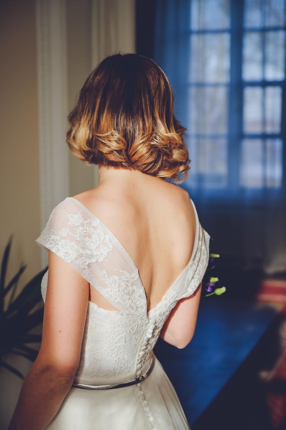 Free Image of Woman in Wedding Dress Looking Out a Window 