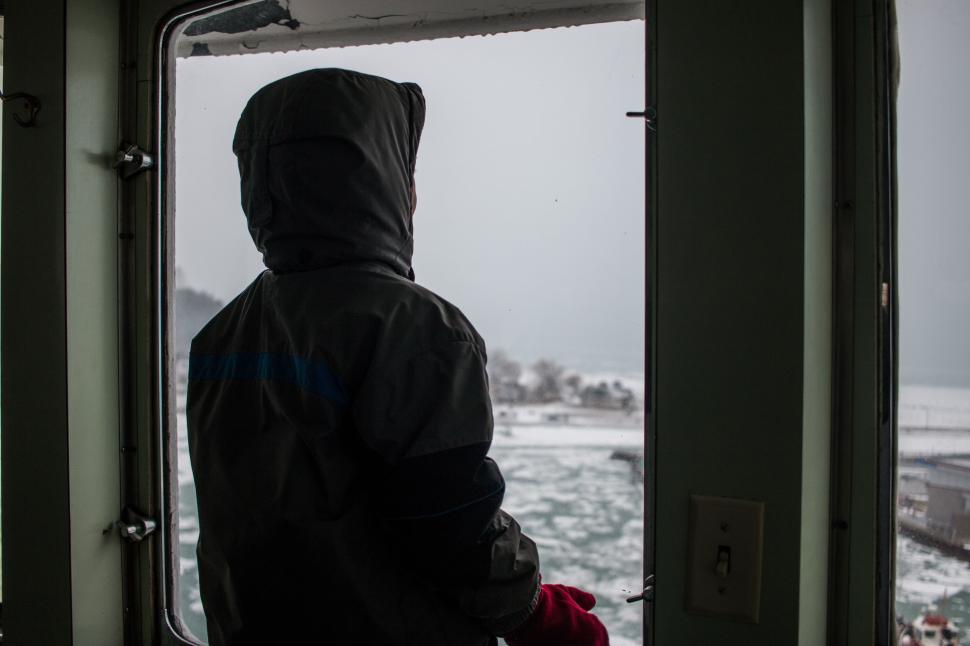 Free Image of Person Standing on Boat Looking Out the Window 