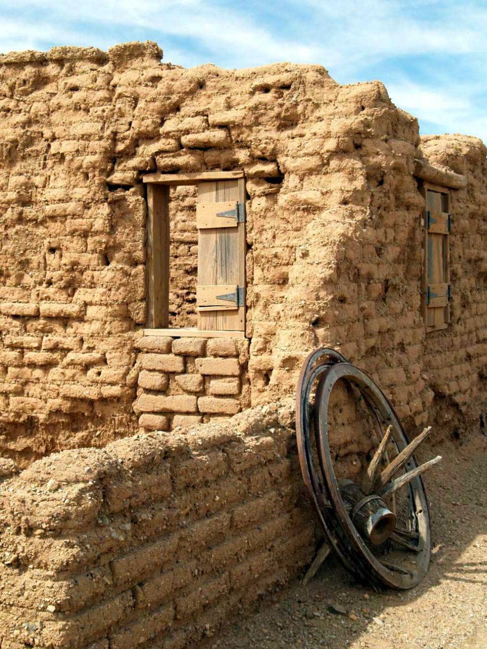 Free Image of Old Building With Leaning Wheel 