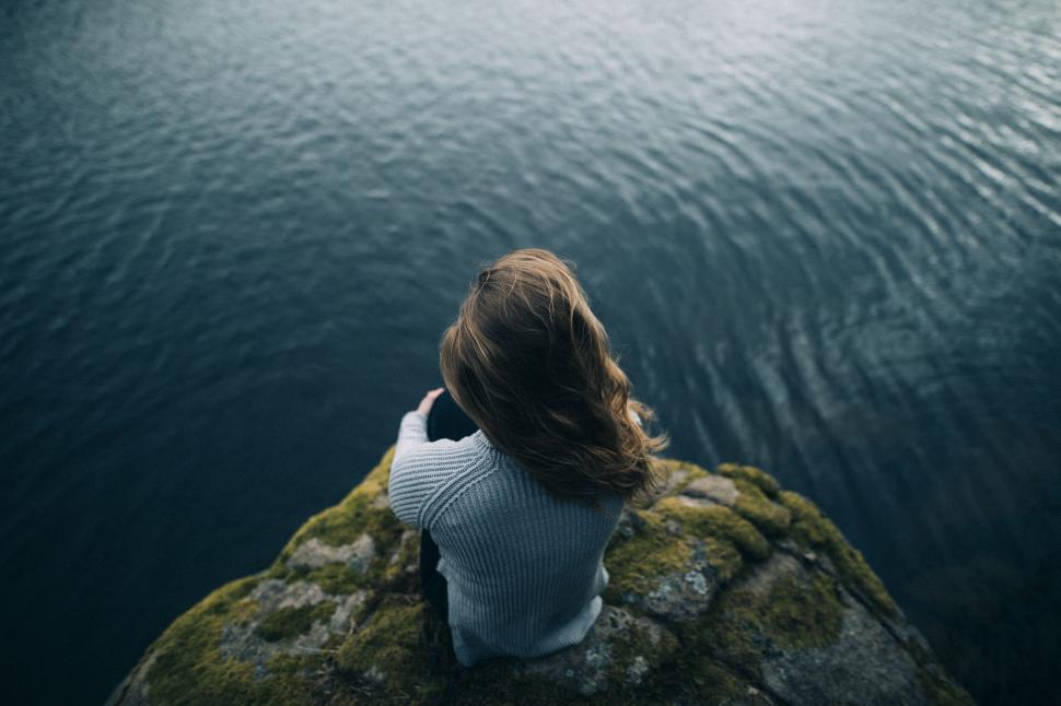 Free Image of Woman Sitting on Rock Looking at Water 