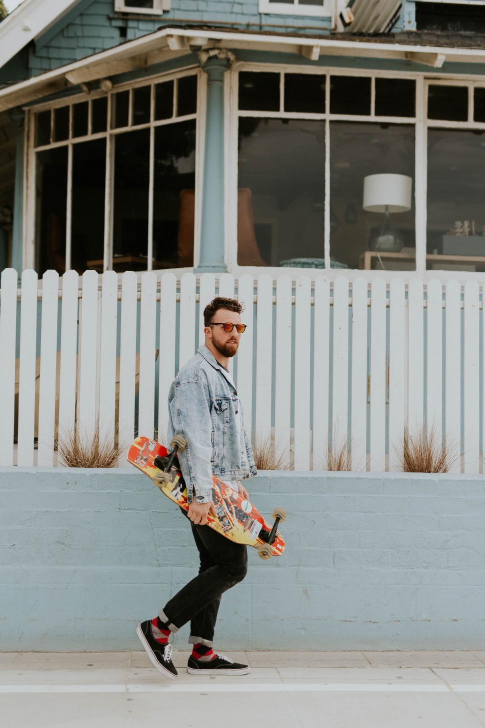 Free Image of Man Walking Down Street Holding Skateboard 