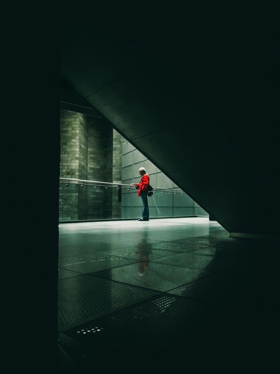 Free Image of Man in Red Jacket Standing in Dark Room 