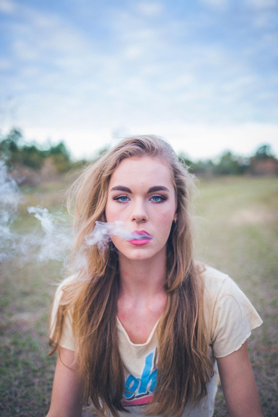 Free Image of Woman Sitting on Ground Smoking a Cigarette 