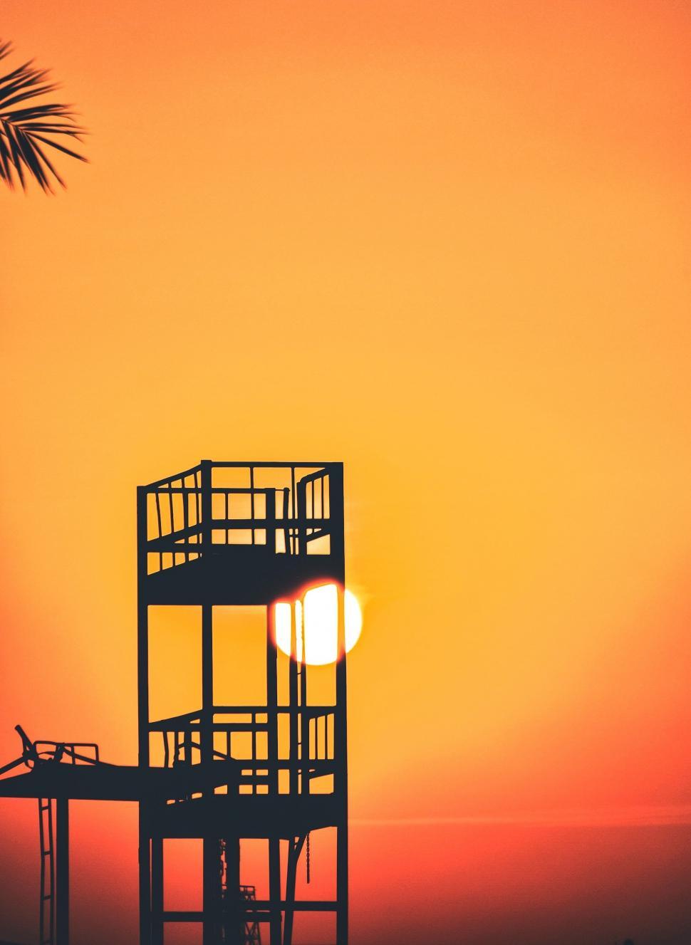 Free Image of The Sun Setting Behind a Lifeguard Tower 