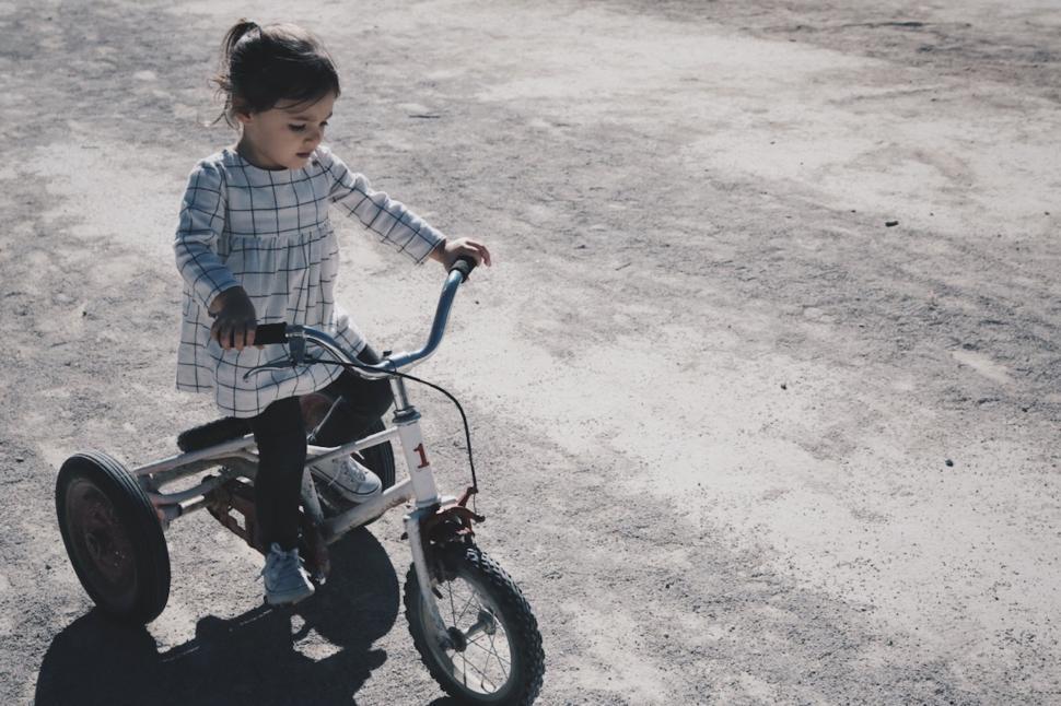 Free Image of Young Girl Riding Bicycle on Dusty Dirt Road 