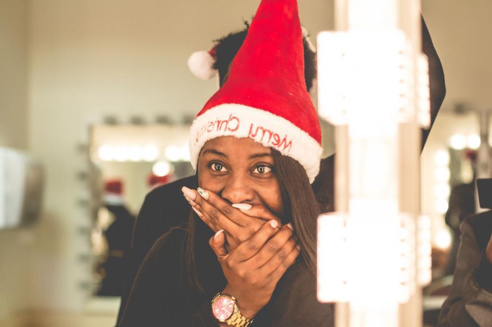 Free Image of Woman in Santa Hat Holding Hands to Mouth 