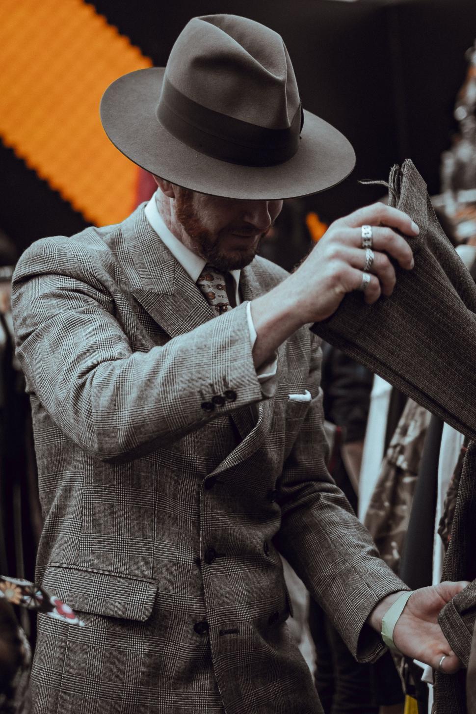 Free Image of Man in Suit and Hat Tying a Tie 