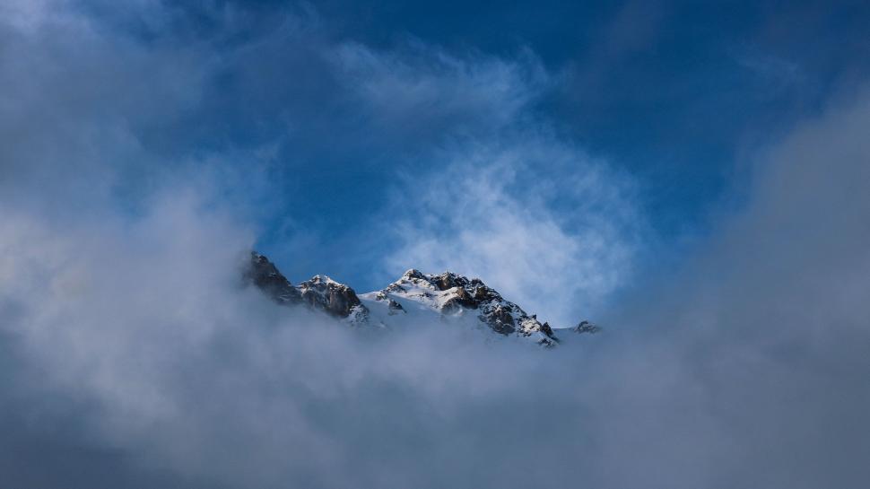 Free Image of Mountain Covered in Clouds Under a Blue Sky 