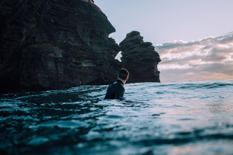 Free Image of Man Standing in Ocean Next to Cliff 